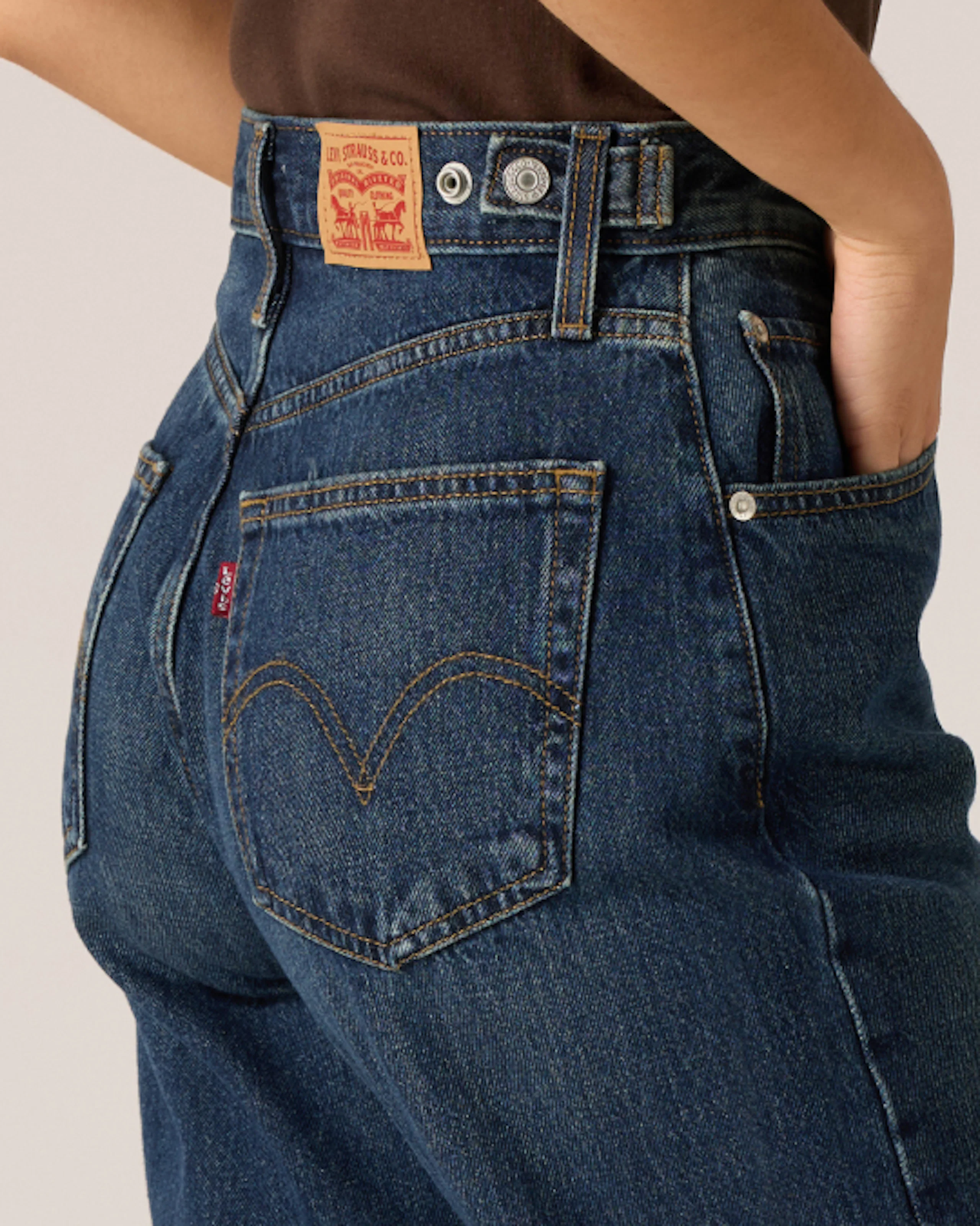 Lähikuva tummansinisissä Levi's-korkeavyötäröisissä farkuissa, joissa näkyy takataskun ikoninen kaareva ompelu ja punainen välilehtilogo.