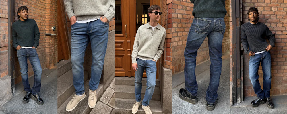 To menn som modellerer blå jeans og strikkegensere, stående og lent mot en mursteinsdøråpning og trappetrinn i et urbant miljø.