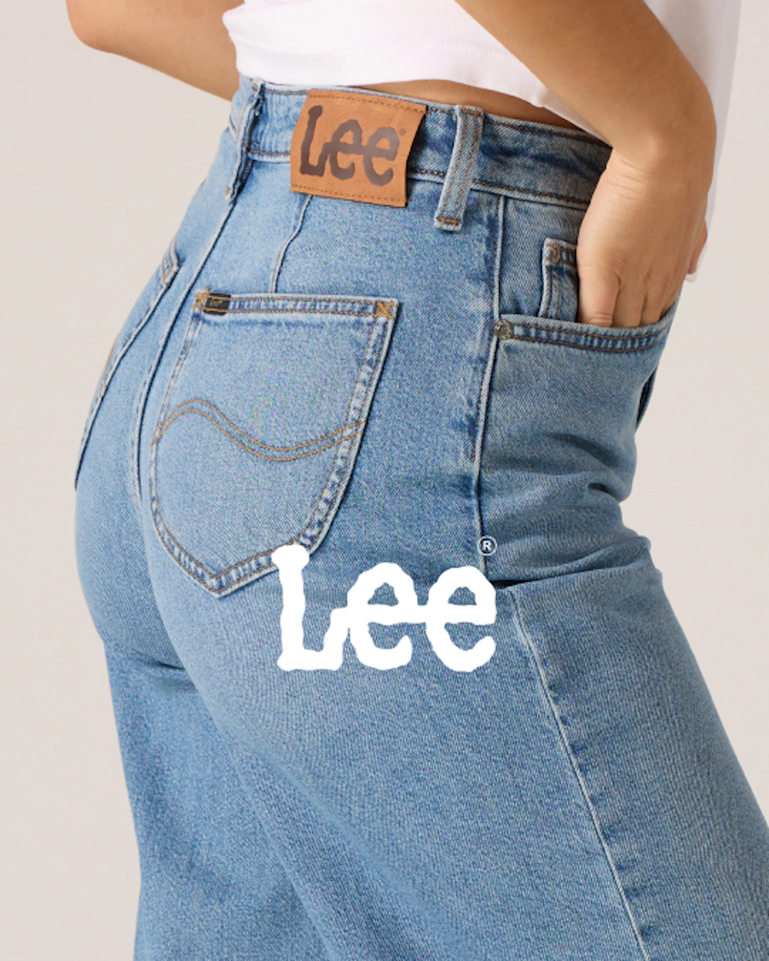 Närbild på en kvinna som bär ljusblå Lee-jeans med hög midja, med fokus på bakfickan med Lees läderlapplogotyp.