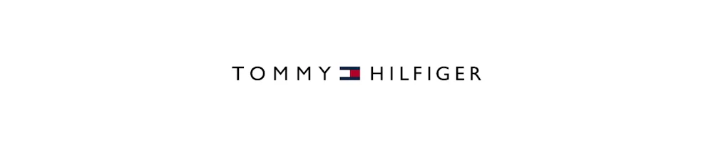 Tommy Hilfiger -logo valkoisella taustalla, teksti tummansinisellä ja pieni punavalkosininen lippukuvake keskellä.