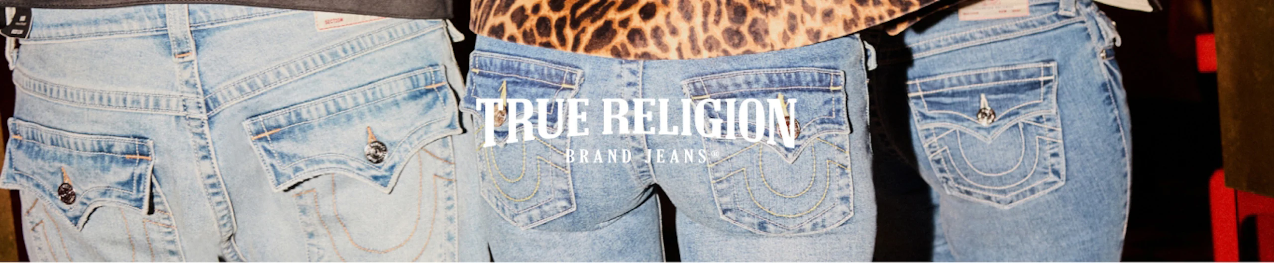 Kolme paria vaaleansinisiä True Religion -farkkuja takaa kuvattuna, keskellä brändin logo.