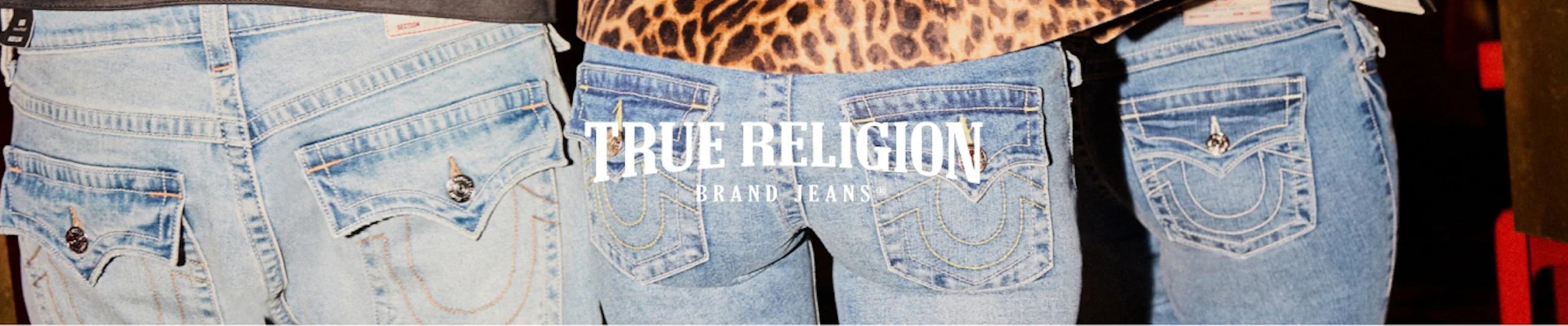 Kolme paria vaaleansinisiä True Religion -farkkuja takaa kuvattuna, keskellä brändin logo.