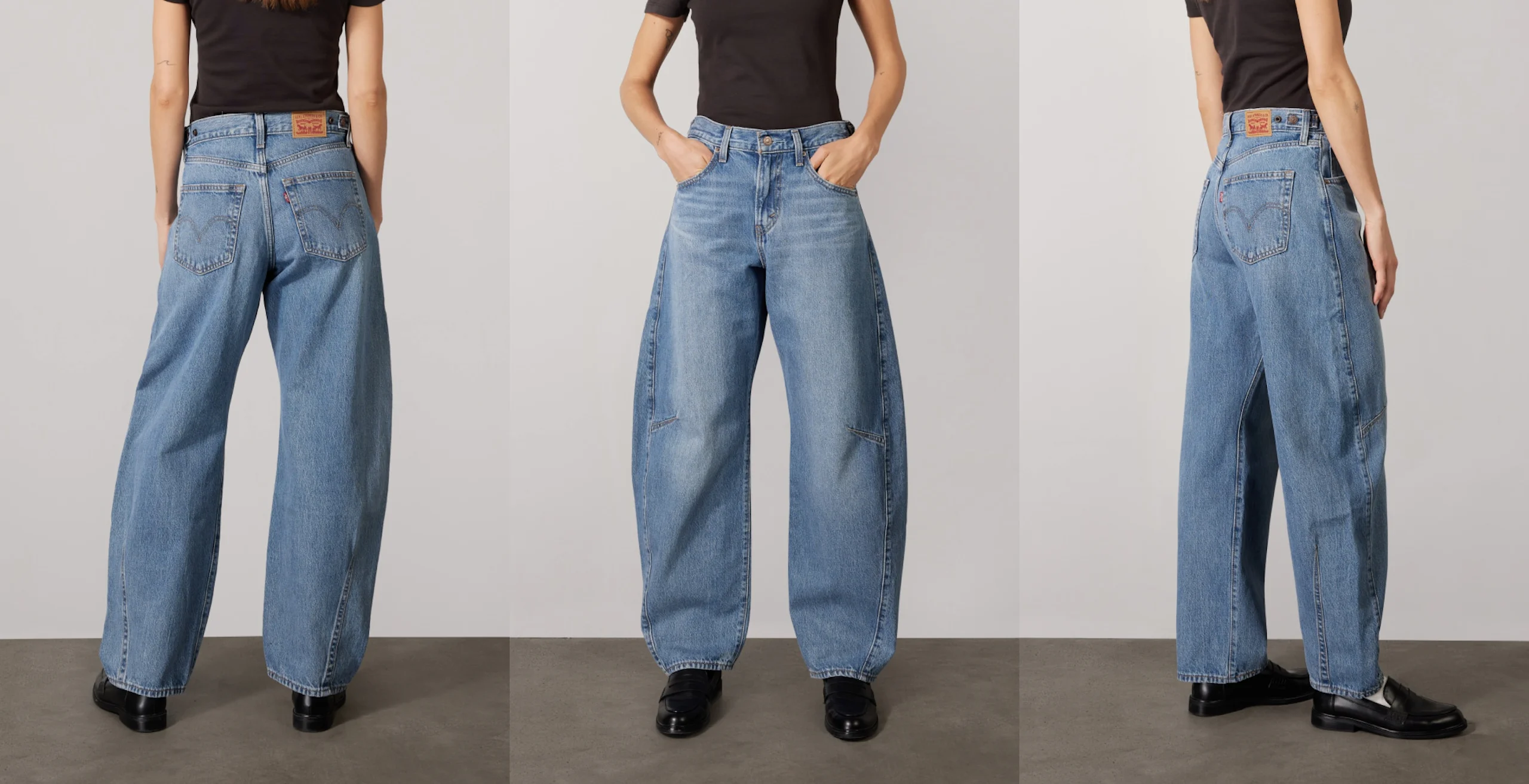 Modell som bär högmidjade, ljusblå vida jeans med sydda bakfickor och händerna i framfickorna poserar på grå studiolayout.