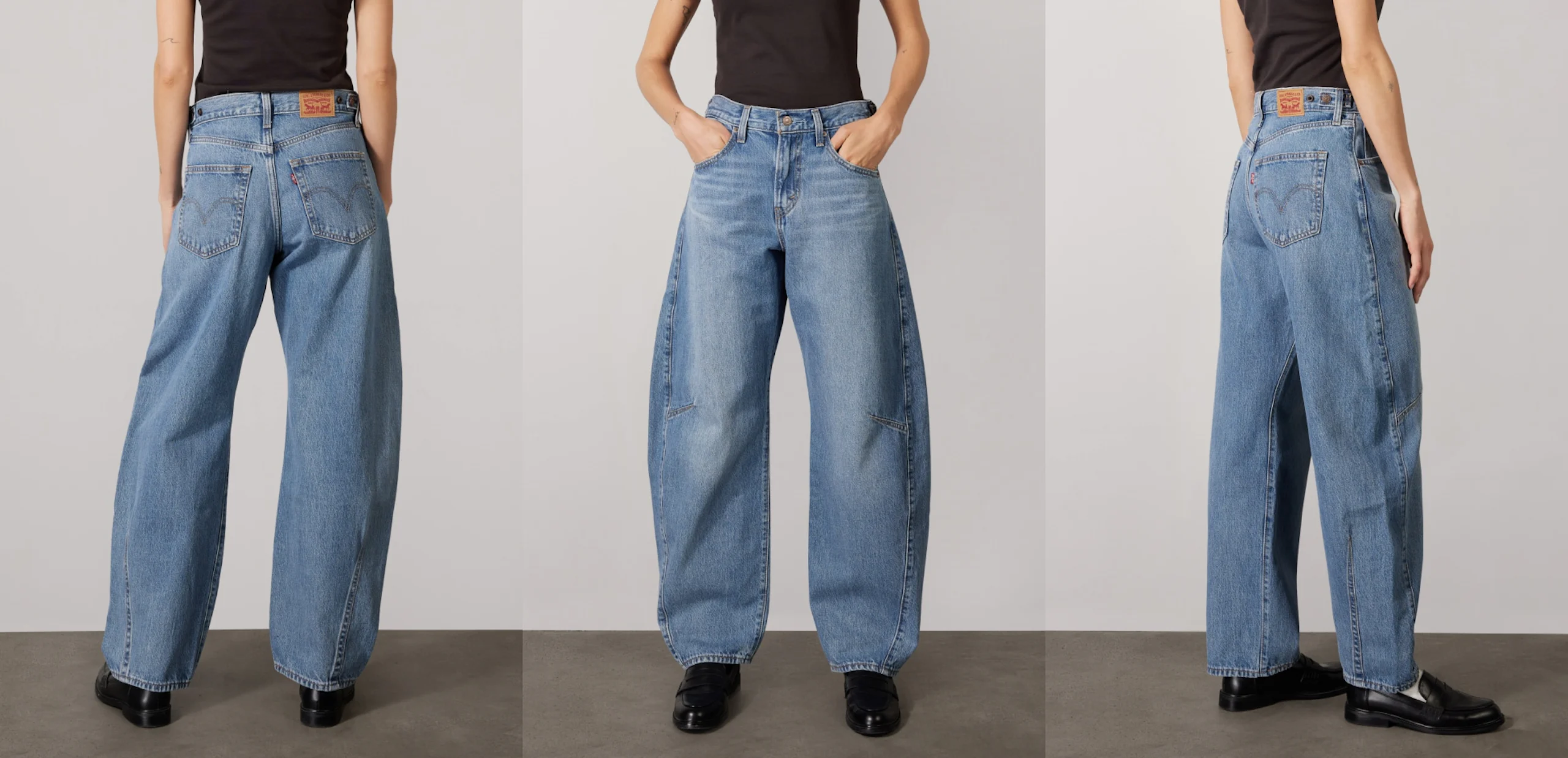 Modell som bär högmidjade, ljusblå vida jeans med sydda bakfickor och händerna i framfickorna poserar på grå studiolayout.