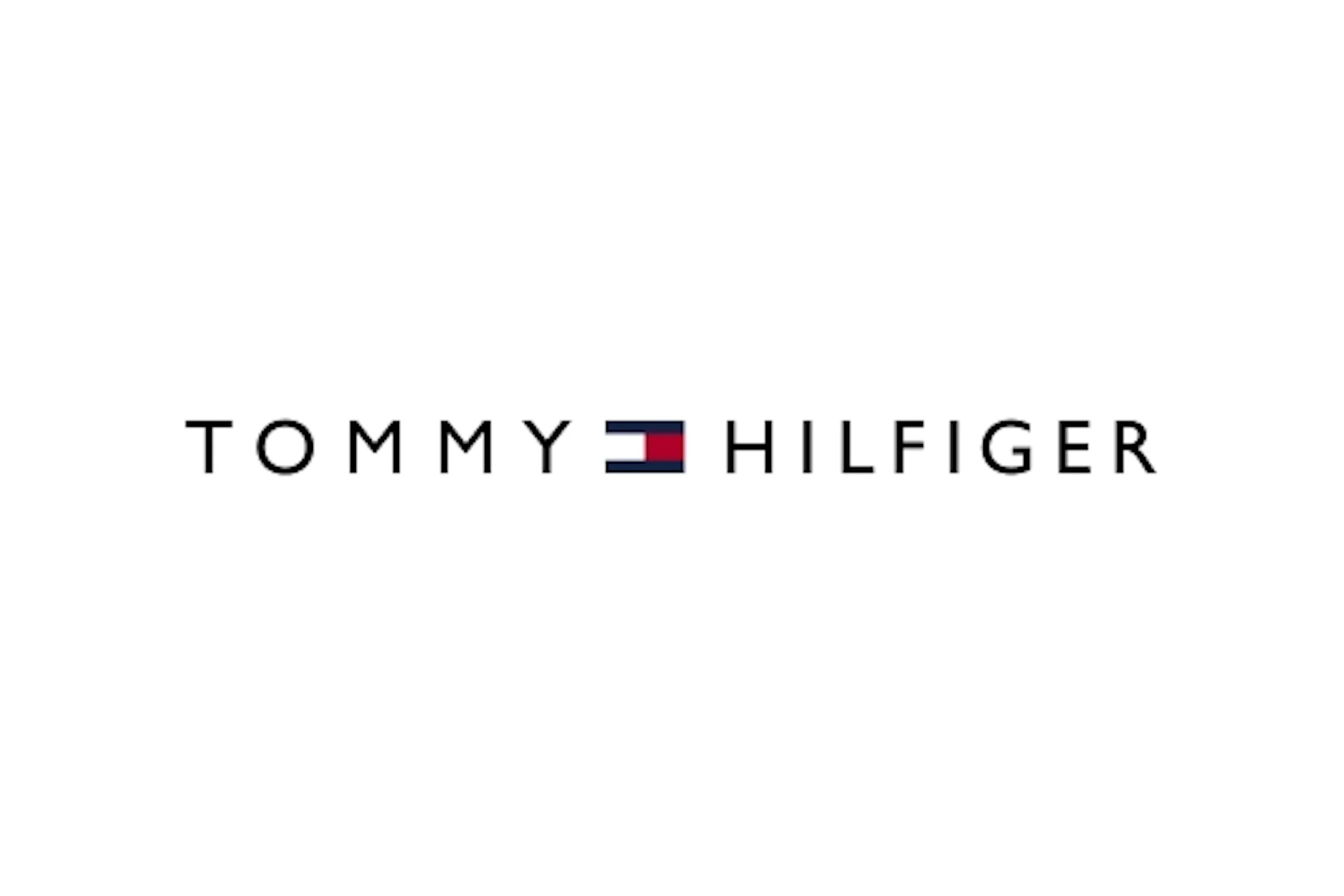 Tommy Hilfiger -logo valkoisella taustalla, teksti mustalla ja pieni punainen, valkoinen ja sininen lippukuvake keskellä.