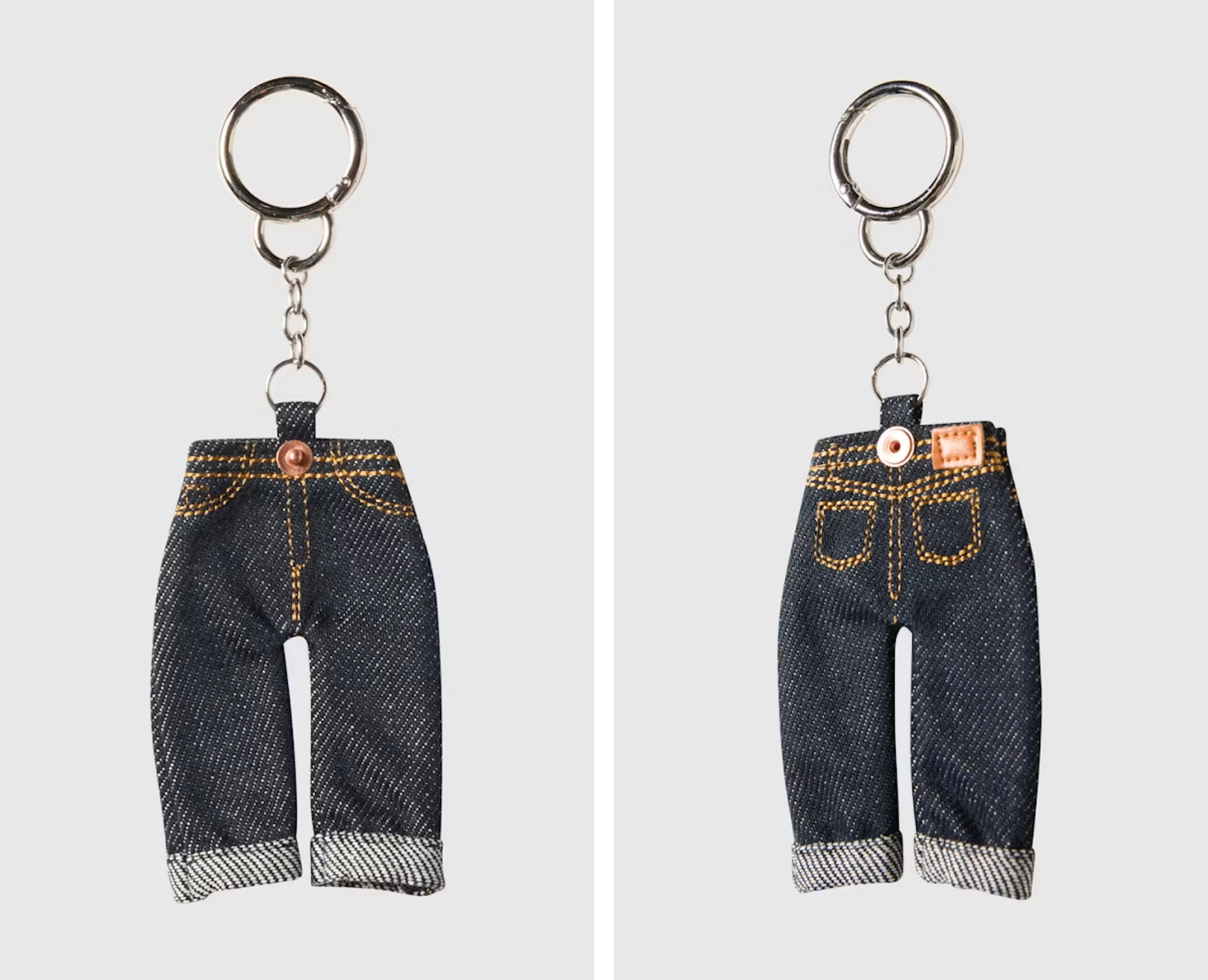 To miniatyr jeans-nøkkelringer i mørk denim med gule sømmer, vist forfra og bakfra, med sølvfarget nøkkelring.